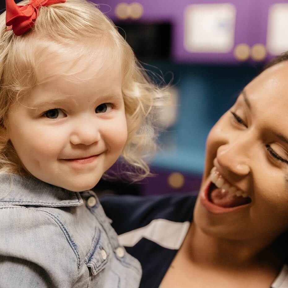 A KidsLife volunteer holds a smiling little girl
