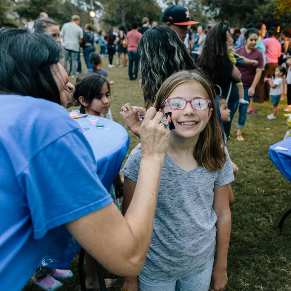 A girl has her face painted at a Block Party