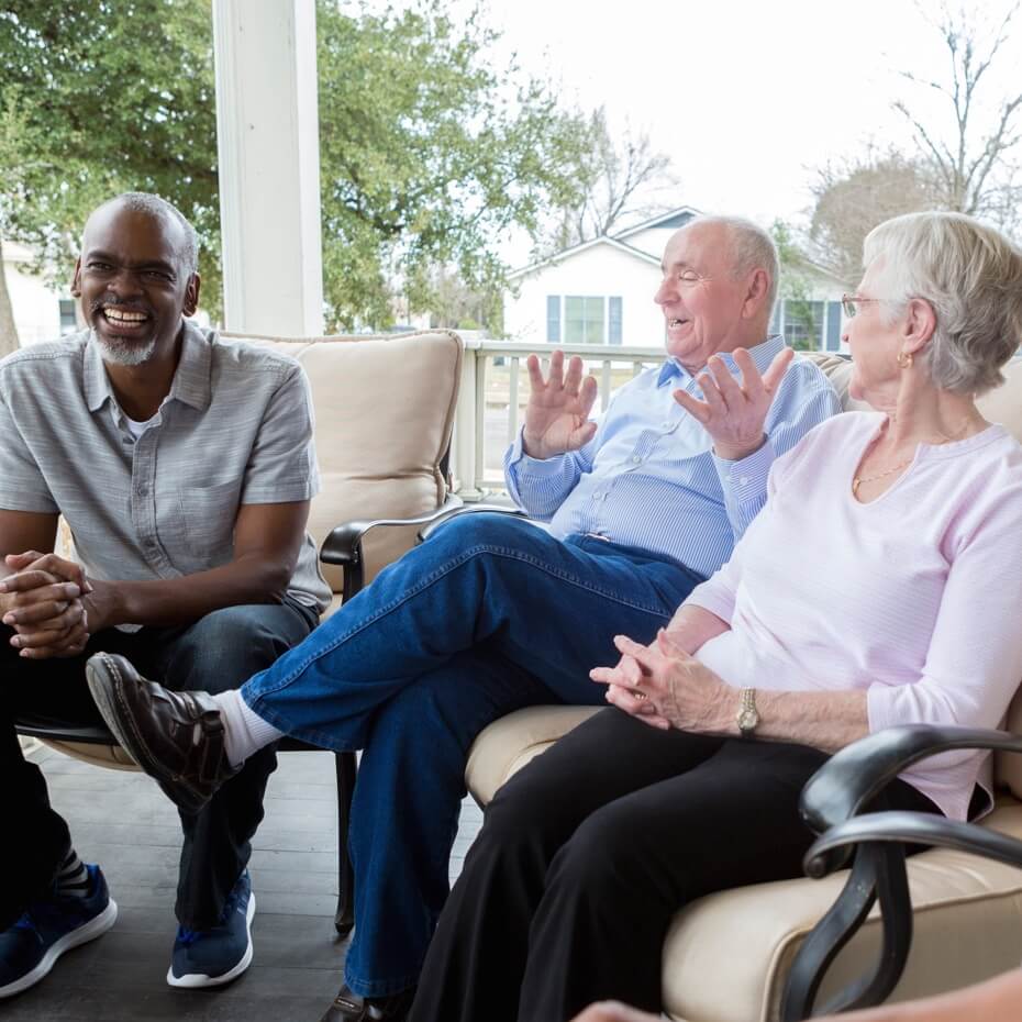 A group of seniors chat on a front porch