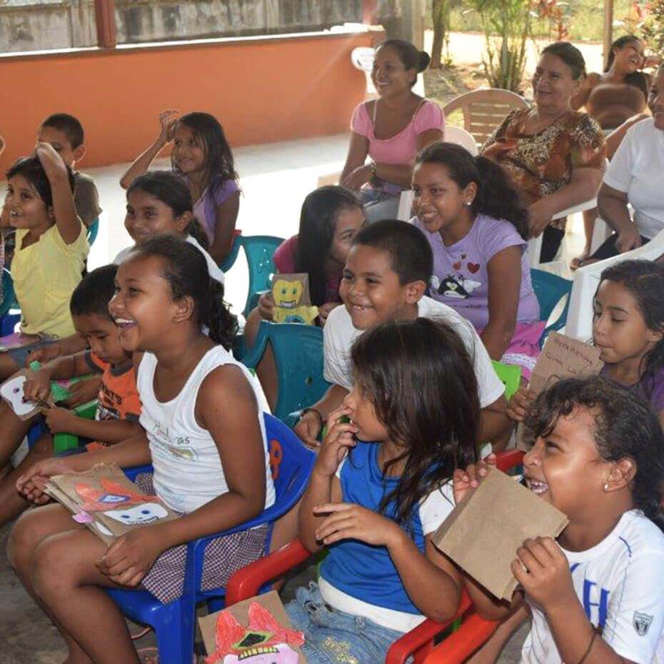 A group of kids laughing while watching a presentation during a mission trip to Honduras.