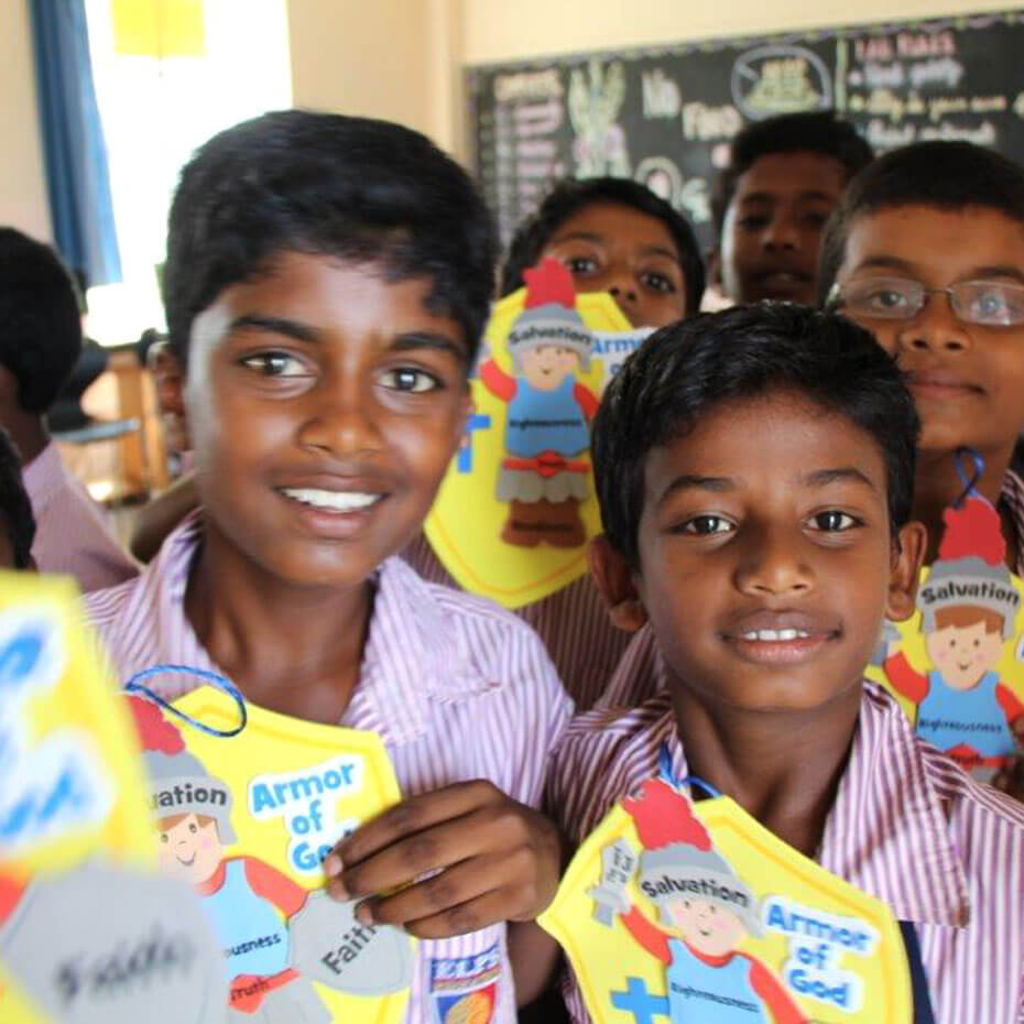 A group of kids smiling and holding up crafts during a mission trip to India.