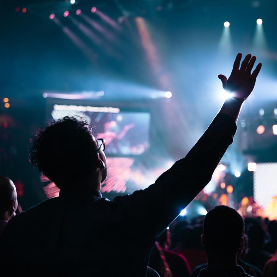 A young adult lifts his hand in worship